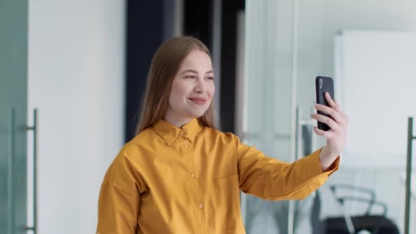 Fiatal, udvarias női irodavezető videohívás külföldi partnerekkel, üzleti adatok online megvitatása az irodában — Stock videók