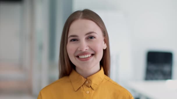 Joven mujer atractiva gerente de oficina sonriendo ampliamente a la cámara, expresando positividad y profesionalismo en la oficina — Vídeos de Stock