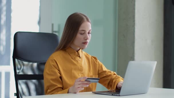 Online payments concept. Young beautiful business lady paying in internet, using laptop and credit card at office — Stockvideo