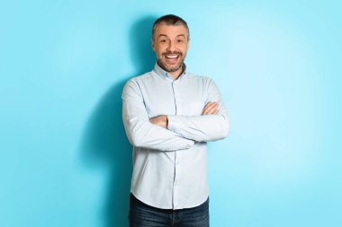 Pozitif Orta yaşlı adam ellerini mavi arkaplanda çapraz pozisyona sokuyor