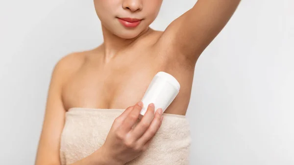 Young Asian woman using applying deodorant in bathroom — Stok fotoğraf