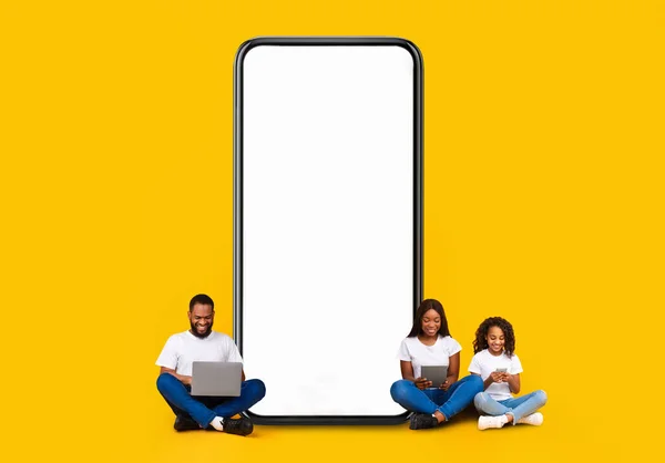 ガジェットを使用して空のスマートフォンの画面を示す黒人家族 — ストック写真