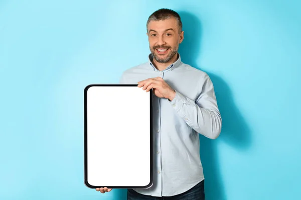 Middle Aged Man Holding Big Digital Tablet On Blue Background — Stockfoto