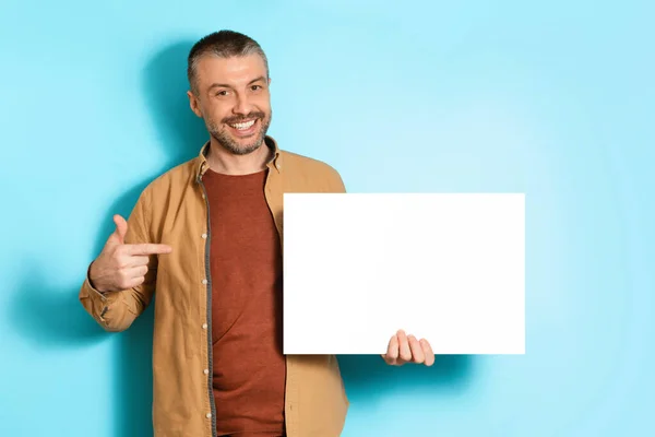 Smiling Man Showing Blank Paper Poster Standing Over Blue Background —  Fotos de Stock