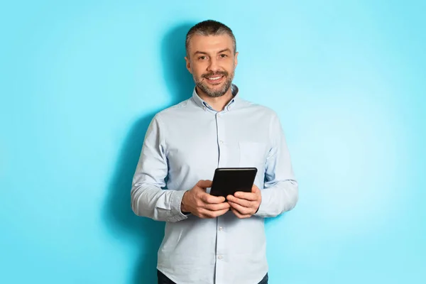 Middle Aged Businessman Holding Digital Tablet Standing Over Blue Background — Stok Foto