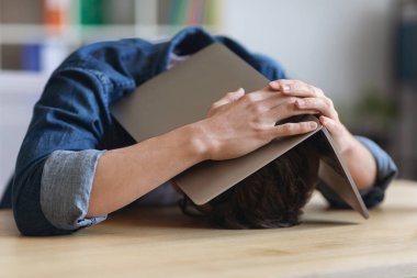 Portrait Of Stressed Young Man Covering His Head With Laptop In Office