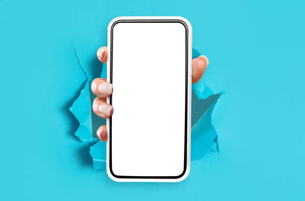 Леди показывает белый пустой экран смартфона, прорывающийся сквозь бумагу — стоковое фото