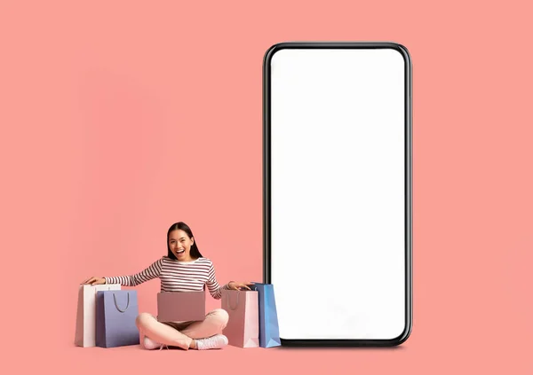 Woman posing with white empty smartphone screen and shopper bags — Stockfoto
