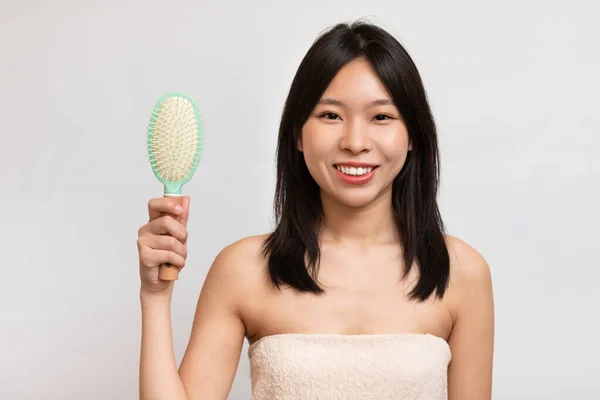 Retrato de mujer asiática alegre cepillándose el pelo — Foto de Stock