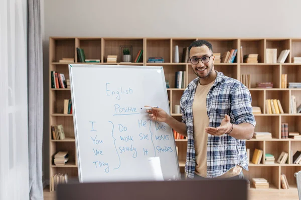 Online education. Portrait of cheerful arab male teacher pointing at whiteboard and explaining English grammar rules — Zdjęcie stockowe