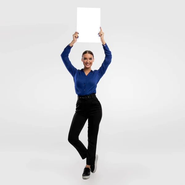 Businesswoman holding blank white advertising billboard at studio — Stockfoto