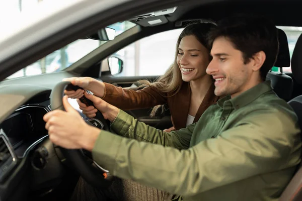 Positive young spouses buying new car, sitting inside modern auto, going on test drive at dealership, free space — Fotografia de Stock