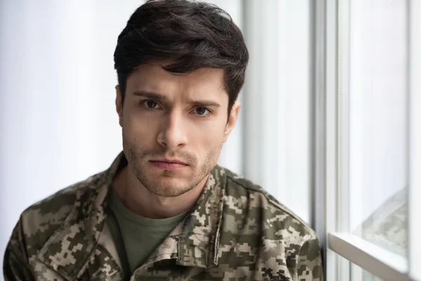 Closeup portrait of upset soldier standing by window — Stok fotoğraf