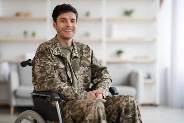 Happy young man soldier sitting in wheelchair, home interior — Stock Fotó