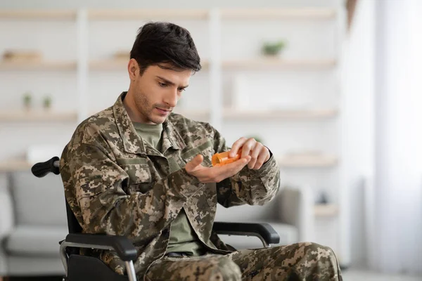 Injured soldier in wheelchair holding jar with medication, copy space — Stock Fotó