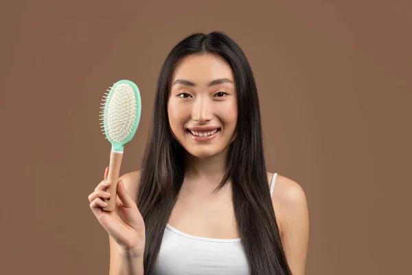 Healthy and beautiful hair concept. Happy korean woman with silky long hair holding brush and smiling at camera — Foto de Stock