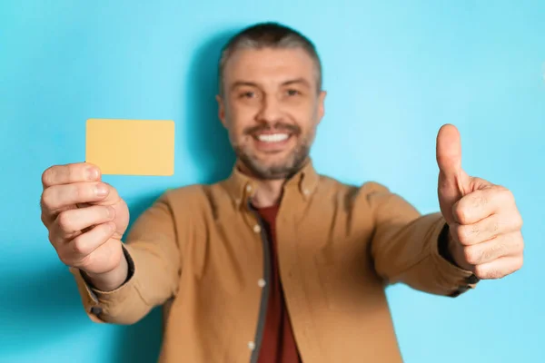 Férfi mutatja a hitelkártya, és mint álló felett kék háttér — Stock Fotó
