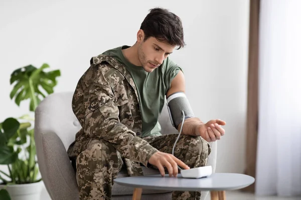 Handsome military man checking blood pressure at home — Stock Fotó