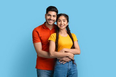 Gülümseyen Orta Doğulu genç bir çiftin portresi. Sarılmak ve kameraya bakmak.