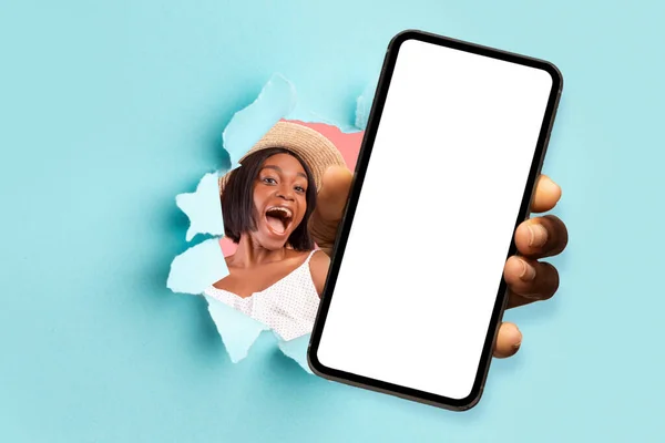 Black lady showing white empty smartphone screen through torn paper — Stockfoto
