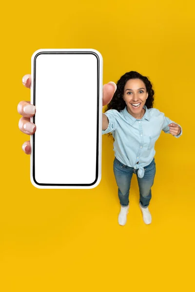 Excited woman showing blank mobile phone screen at studio — Foto Stock