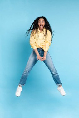 Heyecanlı genç bayan turuncu stüdyoda zıplıyor.