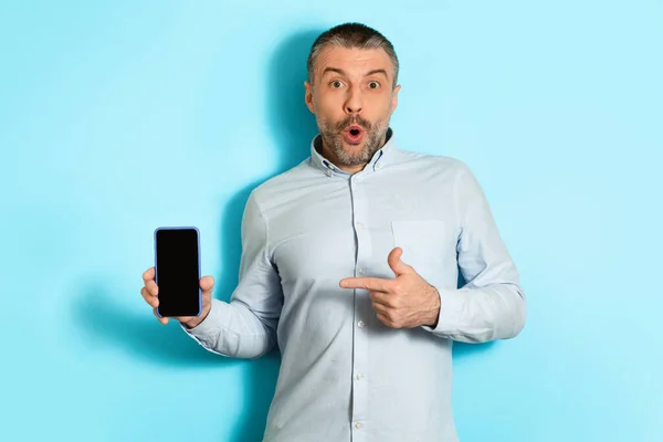 Funny Middle Aged Man Showing Cellphone Screen Over Blue Background — Stockfoto