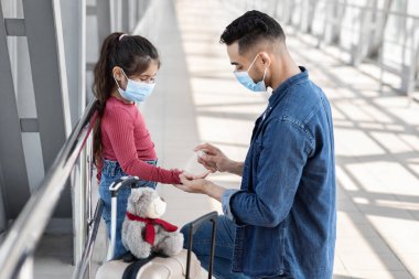 Mikrop Koruma. Babasını havaalanında kızlarının ellerine antibakteriyel sprey sıkarken görmek.