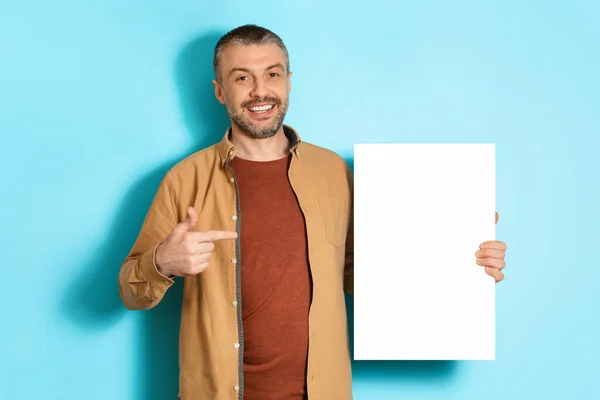 Hombre de mediana edad mostrando libro blanco vacío sobre fondo azul — Foto de Stock