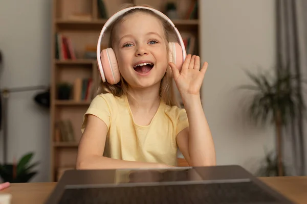 Little Girl Making Video Call Waving Hand To Laptop Indoors