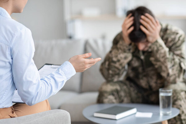 Unrecognizable lady psychologist having conversation with soldier