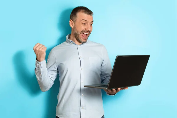 Középkorú férfi gazdaság Laptop Computer Gesturing Igen, kék háttér — Stock Fotó