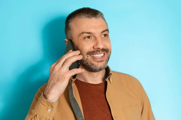 Happy Man beszél a mobiltelefon néz félre a kék háttér — Stock Fotó