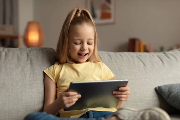 Menina alegre usando Tablet Digital navegando na Internet em casa — Fotografia de Stock