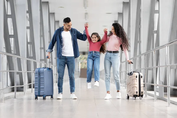 Havalimanında yürürken eğlenen üç kişilik mutlu bir Arap ailesi.