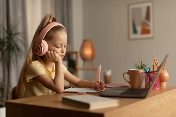 Tired Schoolgirl Learning Online Using Laptop And Taking Notes Indoor — Fotografia de Stock