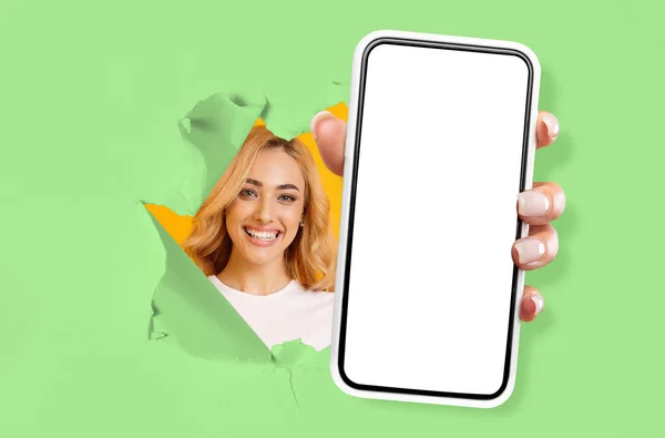 Junge Frau zeigt schwarzen leeren Smartphone-Bildschirm durch zerrissenes Papier — Stockfoto