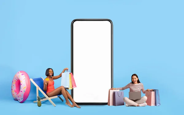 Women posing with white empty smartphone screen and shopper bags — Stockfoto