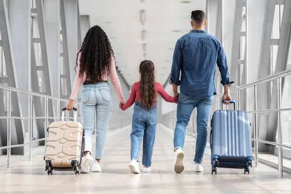 Vista trasera de la foto de la familia llevando maletas mientras caminan juntos en el aeropuerto — Foto de Stock