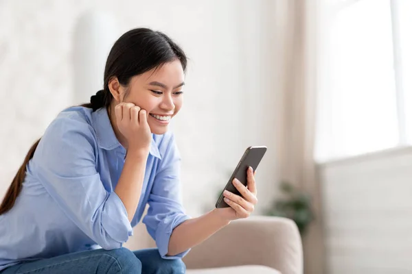Happy chinese lady using mobile phone at home — Foto de Stock