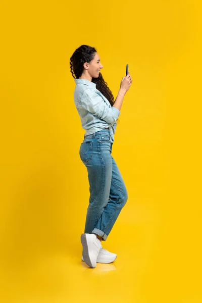 Boldog fiatal nő használja mobiltelefon a stúdióban — Stock Fotó