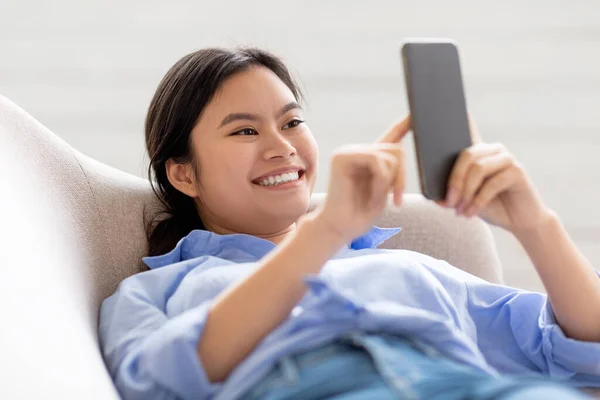 Smiling lady laying on sofa, using cell phone, closeup — 스톡 사진