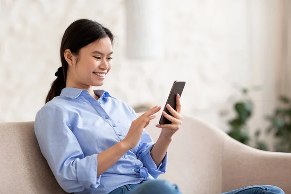 Relaxed japanese woman chilling at home, using smartphone — Foto de Stock