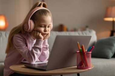Mutsuz liseli kız ev ödevi yaparken dizüstü bilgisayar kullanıyor. Evde sorun yaşıyor.