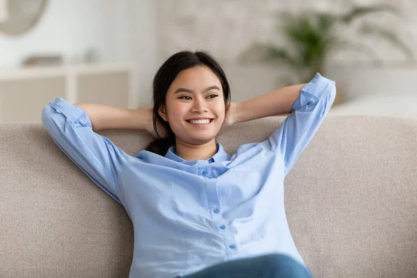 Cute chinese woman resting on sofa at home — Stockfoto