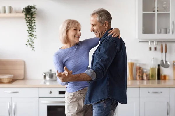 Sevgi dolu yaşlı çift mutfakta eğleniyor, dans ediyor. — Stok fotoğraf