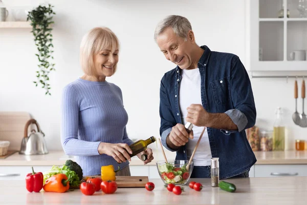 Attractive mature man and woman cooking together at home — Stockfoto