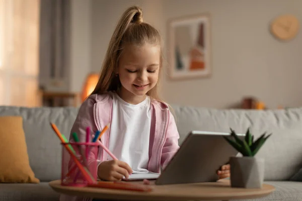 Menina aprendendo usando Tablet e tomar notas em casa — Fotografia de Stock