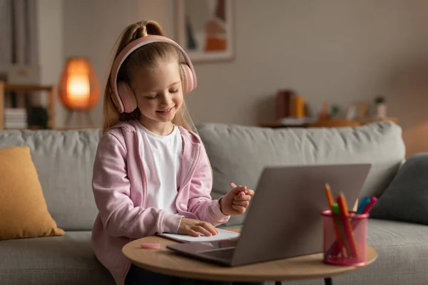 Menina perto do laptop tomar notas fazendo lição de casa on-line em casa — Fotografia de Stock