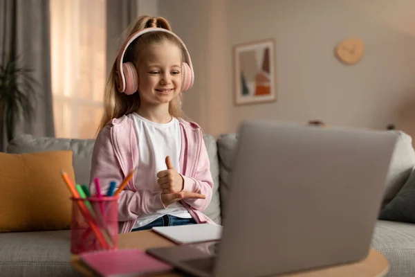 Cheerful Schoolgirl vídeo chamando Gesturing polegares até laptop interior — Fotografia de Stock